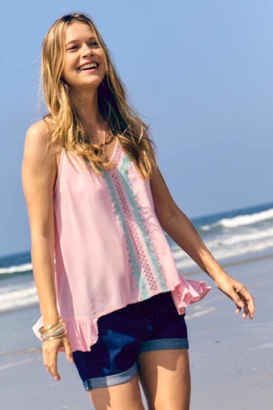 Woman in blush tank top and jean shorts